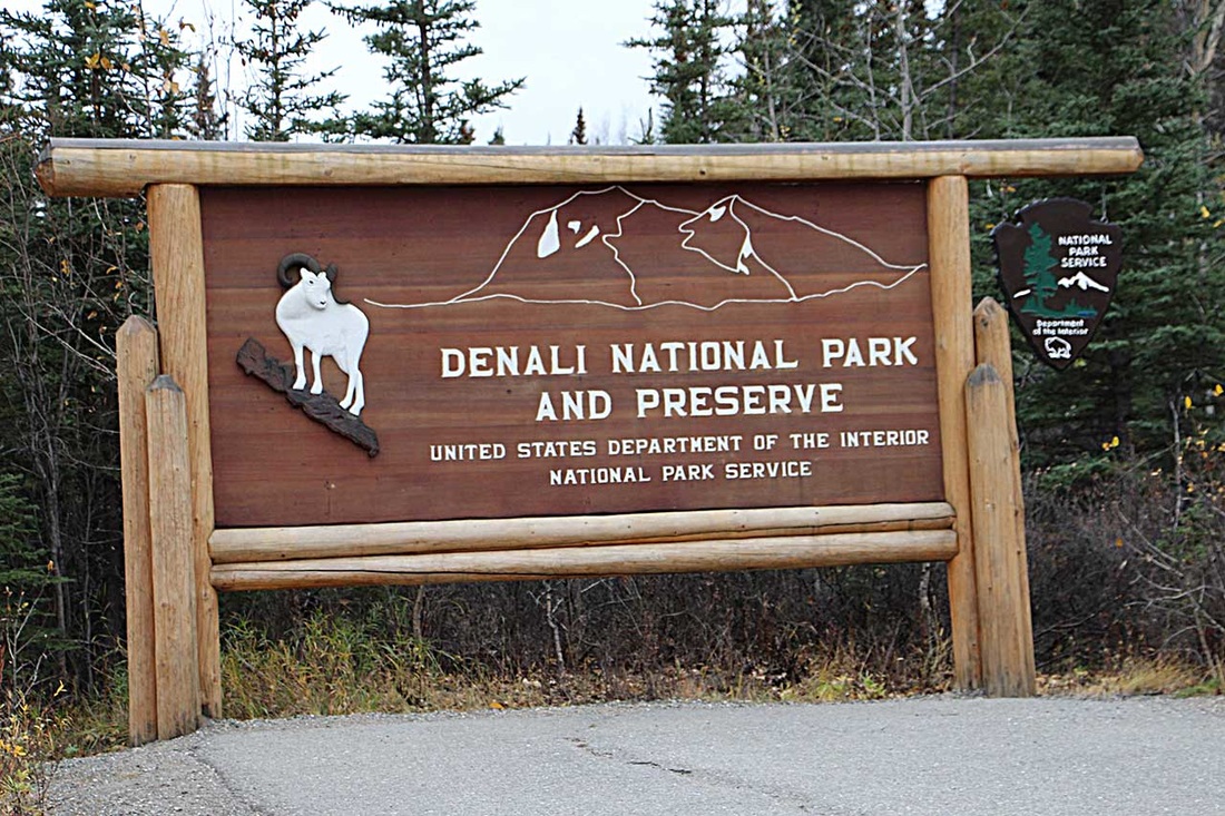Entrance sign to Denali National Park and Preserve surrounded by trees.